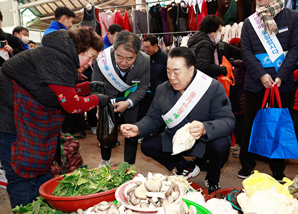 구복규 화순군수(오른쪽)이 설 명절을 맞아 관내 전통시장에서 채소류를 구입하며 상인들과 소통하고 있다 [사진=화순군]