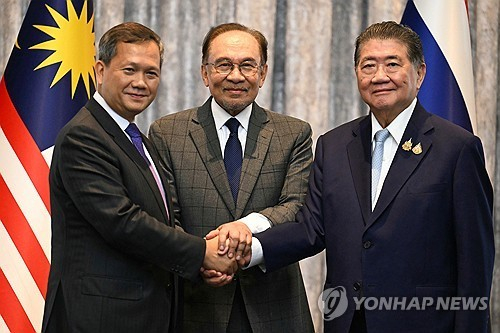 28일(현지시간) 말레이시아 쿠알라룸푸르에서 훈 마네트 캄보디아 총리(사진 왼쪽)와 태국 총리 권한대행인 품탐 웨차야차이 부총리 겸 내무부 장관(오른쪽)이 휴전에 합의한 뒤 회담을 중재한 안와르 이브라힘 말레이시아 총리(가운데)와 함께 손을 잡고 있다 [사진=AP/연합뉴스]
