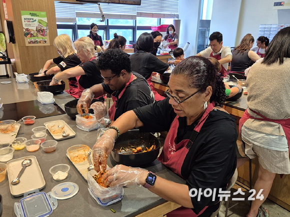 김치 만들기 체험에 참여한 외국인들이 완성된 깍두기를 밀폐용기에 담고 있다. [사진=구서윤 기자]