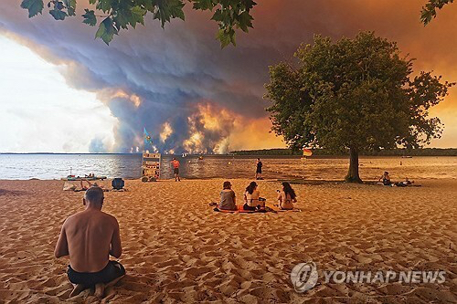 24일 프랑스 남서부 해안가 피서객들 눈앞에 거대한 산불 연기가 피어오르고 있다. [AFP=연합뉴스]