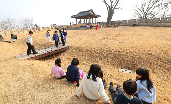 인천 강화군 연미정으로 겨울방학 현장체험학습을 나온 어린이들이 두꺼운 외투를 벗어놓고 잔디에 앉아 휴식하고 있다. [사진=연합뉴스]