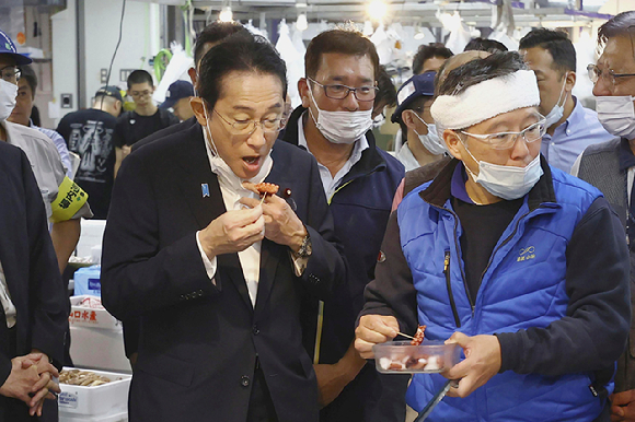 기시다 후미오(오른쪽) 일본 총리가 지난 8월 31일 일본 도쿄의 도요스 수산시장을 찾아 해산물을 맛보고 있다.  [사진=AP/뉴시스]