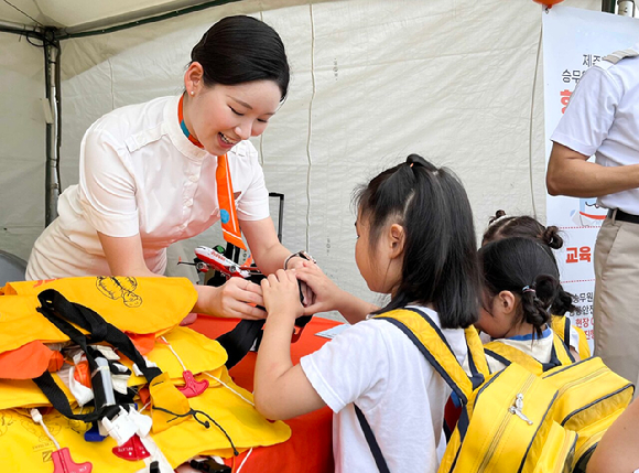 제주항공 객실 승무원들이 지난 26일 제주시 시민 복지타운에서 열린 '제17회 제주 범도민 안전체험 한마당'에서 어린이에게 비상 상황 발생 시 구명조끼 착용 방법을 가르쳐 주고 있다. [사진=제주항공]