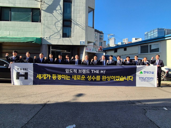 현대건설 관계자들이 30일 서울 성동구에서 열린 성수1지구 주택재개발정비사업 현장설명회에 참석해 하이엔드 주거 브랜드 '디에이치(THE H)'가 적힌 홍보물을 들고 사진을 찍고 있다. [사진=현대건설]