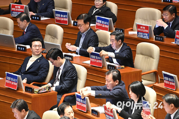 국민의힘 의원들이 9일 국회 본회의에서 국민의힘 나경원 의원이 가맹사업거래의 공정화에 관한 법률 일부개정법률안에 대해 무제한 토론을 하는 가운데 대장동 항소포기 국정조사 실시와 8대 악법 대국민 포기 선언을 촉구하는 인쇄물이 붙어 있다. [사진=곽영래 기자]