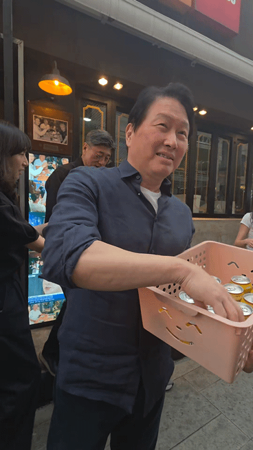 젠슨 황 엔비디아 최고경영자(CEO)가 7일 서울 강남구 삼성동 깐부치킨 앞에서 시민들과 취재진에게 후라이드치킨을 나눠주고 있다. 왼쪽 뒤편에는 SK하이닉스의 HBM 과자가 담긴 상자가 보인다. [사진=박지은 기자]