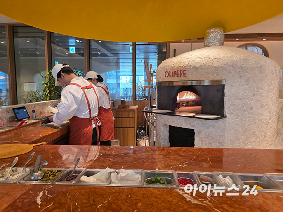 올리페페 강남점 내부. 한쪽 벽면에는 와인이 진열돼 있고, 매장 중앙에는 대형 피자 화덕이 자리하고 있다. [사진=구서윤 기자]