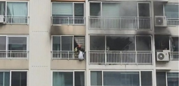 13일 안산의 한 아파트 11층에서 발생한 화재를 피해 외부 베란다에 매달려 있던 여고생이 소방대원에 의해 구조되고 있다. [사진=경기도소방재난본부]