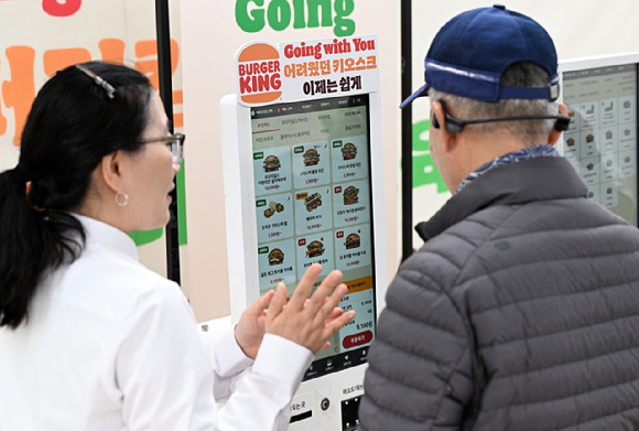 버거킹 직원이 어르신을 대상으로 키오스크 사용법을 알려주고 있는 모습. [사진=버거킹 제공]