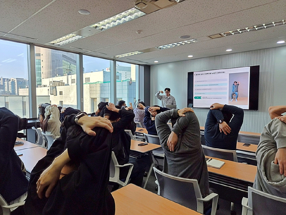 동국시스템즈 임직원들이 근골격 케어 프로그램에 참석해 전문 강사의 지도에 따라 어깨 스트레칭 실습을 진행하고 있다. [사진=동국시스템즈]