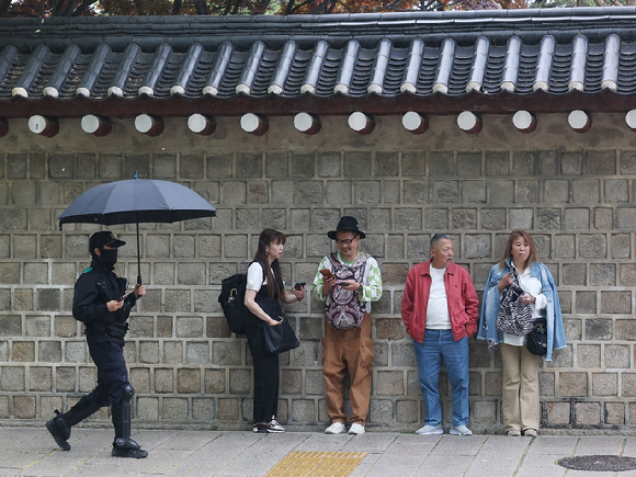 서울 종로구 경복궁 인근에서 우산이 없는 외국인 관광객들이 비를 피하고 있다. [사진=연합뉴스]