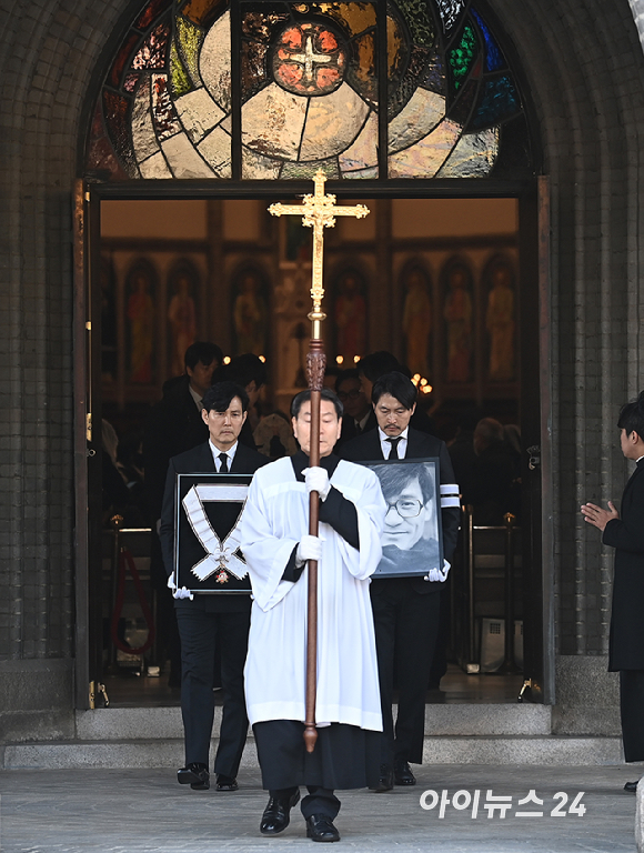 9일 서울 중구 명동성당에서 열린 故 안성기의 장례 미사가 끝난 뒤 영결식을 위해 고인의 영정과 금관문화훈장을 든 배우 정우성, 이정재가 영결식장으로 향하고 있다. [사진=곽영래 기자]