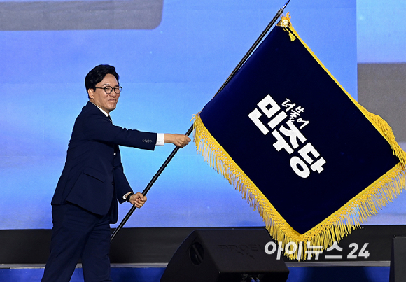 김민석 더불어민주당 신임 당 대표가 17일 대전 컨벤션센터에서 열린 제3회 더불어민주당 정기 전국당원대회에서 당 대표로 선출된 뒤 당기를 흔들고 있다. [사진=곽영래 기자]