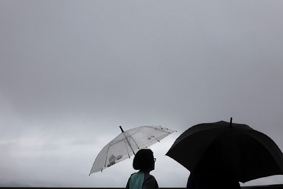 지난 24일 서울 중구 남산에서 우산을 쓴 시민들이 도심을 바라보고 있다. [사진=뉴시스]