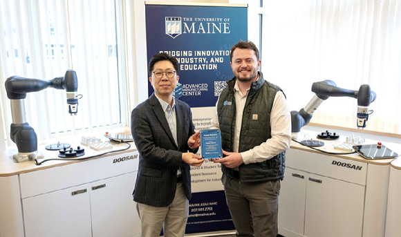 김현수 두산로보틱스 상무(왼쪽)가 브래들리 덴홀름(Bradley Denholm) 메인대학교 첨단제조센터 부소장과 기념사진을 촬영하고 있다. [사진=두산]