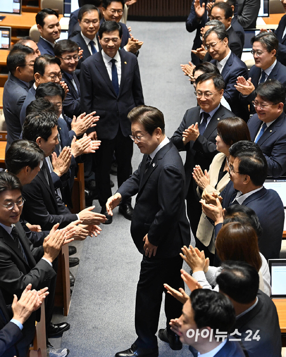 이재명 대통령이 26일 국회에서 열린 본회의에서 추가경정예산 시정연설을 하기 위해 입장하며 의원들과 인사를 하고 있다. [사진=국회사진기자단]