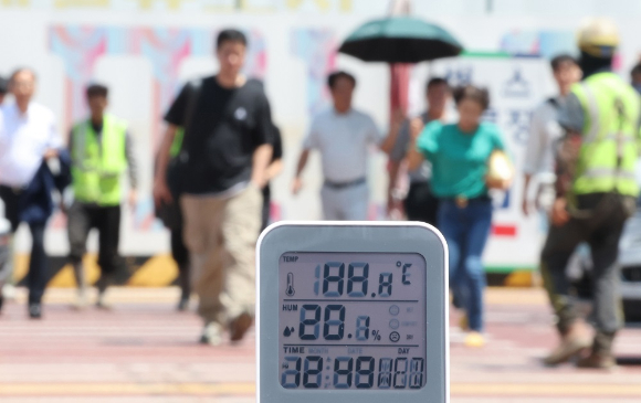 서울 강남구 한 공사현장 부근 횡단보도에서 시민들이 이동하고 있다. 철제 횡단보도에서 지열이 올라와 50도를 넘어서자 온도계에 측정불가 표시가 나오고 있다. [사진=연합뉴스]