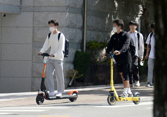 서울의 한 거리에서 안전 장비를 착용하지 않은 시민들이 전동 킥보드를 이용하고 있는 모습 [사진=뉴시스]