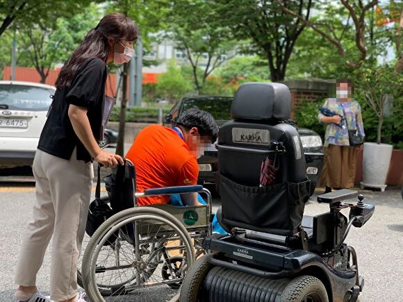 광주광역시 광산구 장애인복지관에서 한 장애인이 휠체어 상태를 살펴보고 있다. [사진=광주 광산구]