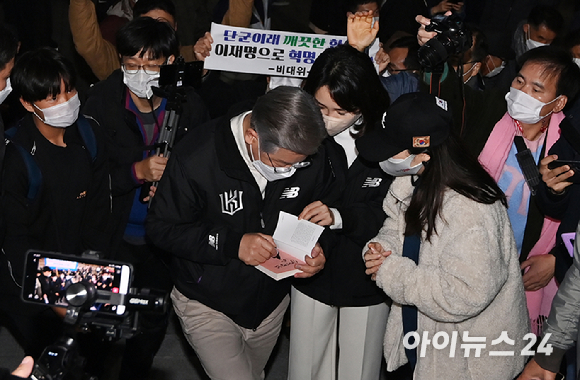 이재명 더불어민주당 대선 후보와 부인 김혜경 씨가 18일 오후 서울 고척스카이돔에서 열리는 '2021 신한은행 SOL KBO리그' KT 위즈와 두산 베어스의 한국시리즈 4차전을 찾아 입장하기 전 저서에 사인을 하고 있다. [사진=김성진 기자]