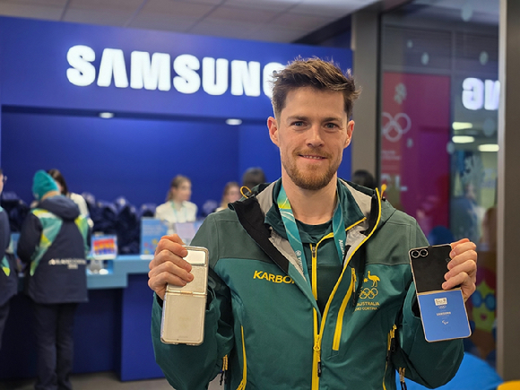 브렌던 코리 호주 스피드 스케이팅 선수가 밀라노 올림픽 선수촌 내 삼성 체험관에 방문해 갤럭시 Z 플립7 올림픽 에디션과 지난 베이징 동계올림픽 갤럭시 Z 플립3 올림픽 에디션을 함께 보여주고 있다. [사진=삼성전자]