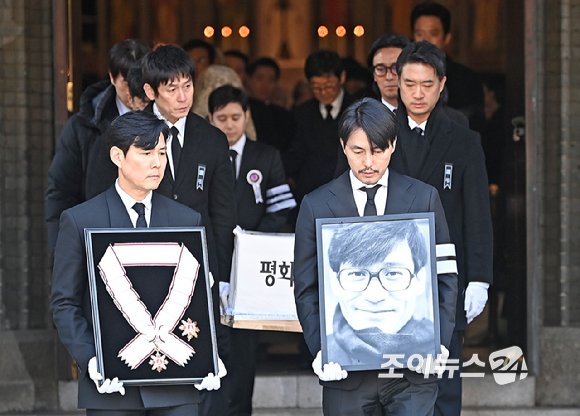 9일 서울 중구 명동성당에서 열린 故 안성기의 장례 미사가 끝난 뒤 영결식을 위해 고인의 영정과 금관문화훈장을 든 배우 정우성, 이정재가 영결식장으로 향하고 있다. [사진=곽영래 기자]