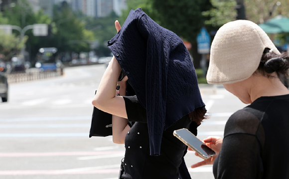 무더운 날씨가 이어지면서 전국 대부분 지역에 폭염특보가 발효된 1일 서울 광화문사거리에서 한 시민이 옷으로 햇볕을 피하고 있다. [사진=연합뉴스]