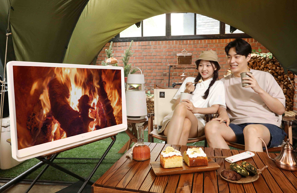 LG전자 모델들이 서울시 강남구에 위치한 캠핑 카페 글락에서 LG 룸앤TV 신제품으로 콘텐츠를 감상하고 있다. [사진=LG전자]