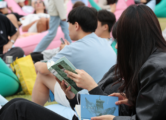 지난 13일 서울 종로구 광화문 광장 서울 야외도서관 책마당에서 한강 작가의 노벨문학상 수상을 축하하기 위한 마련된 특별 전시에서 시민들이 한강 작가의 책을 읽고 있다. [사진=뉴시스]