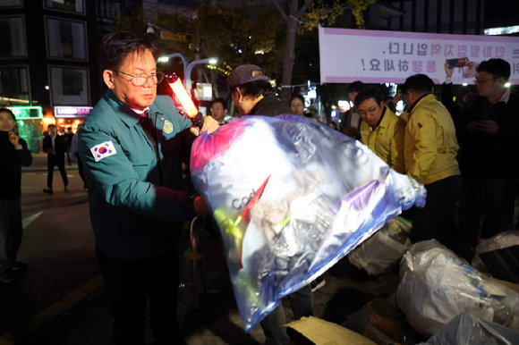 박강수 구청장이 지난해 10월 27일 홍대 안전관리 점검 중 보행에 위험이 되는 적치 쓰레기를 옮기고 있다. [사진=마포구청]