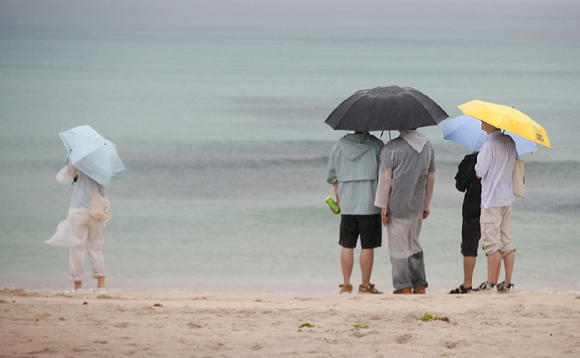 지난달 27일 제주시 구좌읍 월정해수욕장에서 우산을 쓴 관광객들이 바다를 바라보고 있다.  [사진=뉴시스]