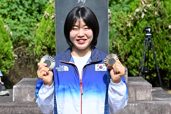 허석 의사 추모기적비 앞에서 허미미 선수가 은메달 동메달을 보이고 있다. [사진=군위군]