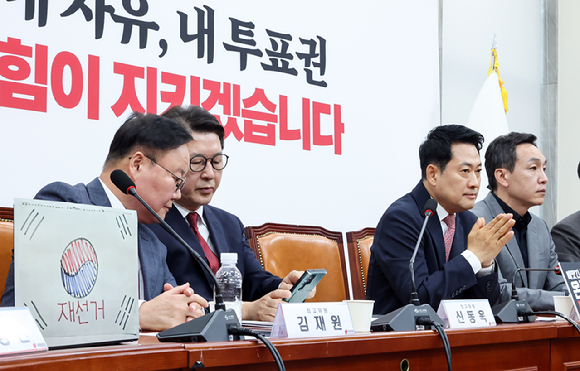 6&middot;3 지방선거에서 불거진 투표용지 부족 사태와 관련해 재선거를 주장하고 있는 국민의힘 장동혁 대표(오른쪽)가 8일 국회에서 열린 최고위원회의에서 생각에 잠겨 있다. 왼쪽에 조광한 최고위원이 자신의 노트북 앞에 붙여 놓은 태극기에 '재선거'가 적힌 그림이 보인다. 2026.6.8 [사진=연합뉴스]
