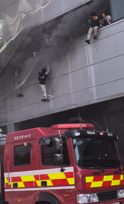 20일 오후 대전 대덕구 문평동 한 자동차부품 제조 공장에서 불이 나 검은 연기가 치솟는 가운데 직원들이 탈출을 위해 필사적으로 뛰어내리고 있다. 2026.3.20 [독자 김영수 씨 제공]