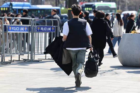 6일 서울 종로구 광화문 네거리에서 반팔 티셔츠를 입은 시민이 외투를 손에 들고 이동하고 있다. [사진=연합뉴스]
