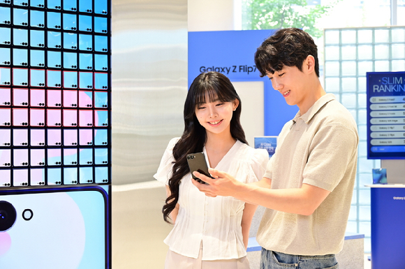 삼성스토어 홍대 '갤럭시 스튜디오'에서 '갤럭시 Z 플립7'의 넓어진 커버 디스플레이를 형상화한 아트 월 앞에서 '갤럭시 Z 플립7'을 사용해보는 모습 [사진=삼성전자]