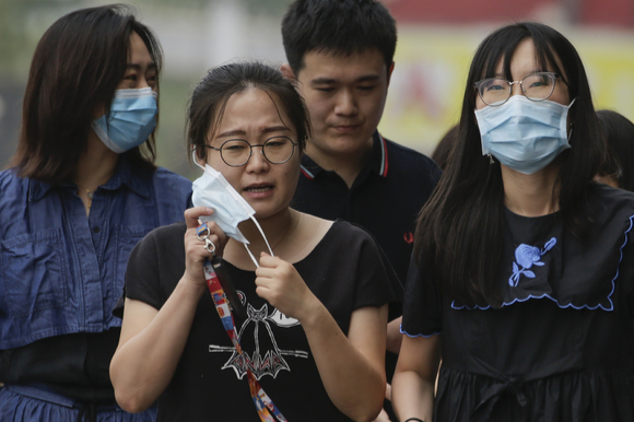 [베이징=AP/뉴시스] 중국 베이징에서 신종 코로나바이러스 감염증(코로나19) 예방을 위해 마스크를 쓴 동료들과 함께 걷던 한 여성이 답답한 듯 마스크를 벗고 있다. [사진=뉴시스]