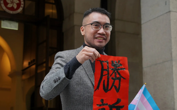 홍콩 트랜스젠더 활동가 헨리 에드워드 쯔가 지난 6일 홍콩 법원의 판결을 환영하며 '승소'라고 적힌 종이를 들어 보인 모습이다. [사진=HKFP 캡처]