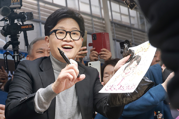 국민의힘 한동훈 전 대표가 22일 서울 동대문구 경동시장을 방문해 상인에게 사인해주고 있다. 2026.3.22 [사진=연합뉴스]