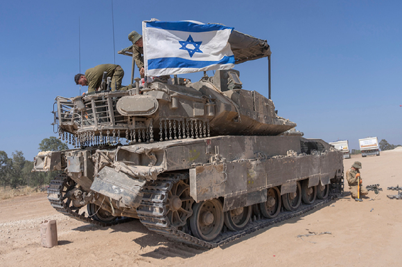 15일(현지시각) 이스라엘 남부, 가자지구 국경 인근에 주둔 중인 이스라엘 군인이 무장병력수송장갑차(APC)에 국기를 부착하고 있다. [사진=뉴시스]