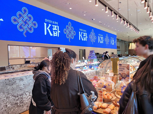 지난 19일 서울 종로구에 위치한 파리바게뜨 광화문 1945점을 찾은 외국인 고객들이 'K파바' 비전이 적용된 특화 제품를 구경하고 있다. [사진=파리바게뜨]