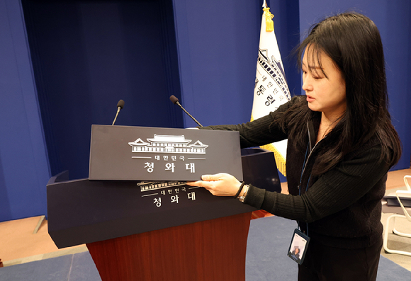 용산 대통령실 이전 작업을 본격화한 21일 청와대 브리핑룸에서 한 직원이 탈부착 업무표장을 설치하고 있다. 2025.12.21 [사진=연합뉴스]