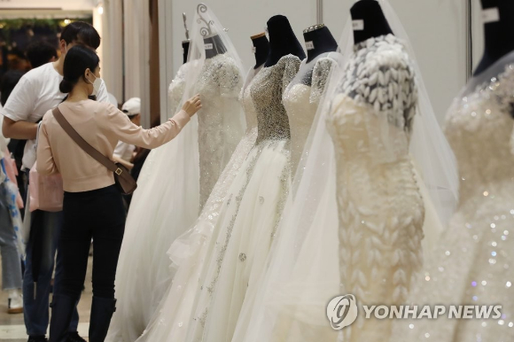 웨딩박람회에서 예비 신랑 신부들이 웨딩드레스를 둘러보고 있다. [사진=연합뉴스]
