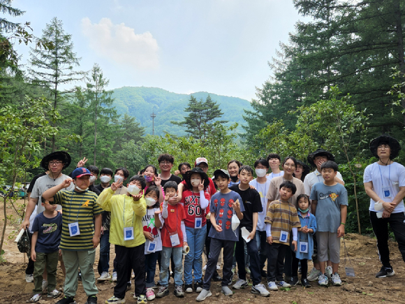 두나무 임직원과 가족들이 국립 양평 치유의 숲에서 진행된 교통약자를 위한 작은숲 조성 봉사활동을 마치고 기념사진을 찍고 있다. [사진=두나무]