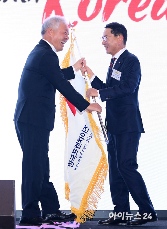 (왼쪽부터)정현식 전 한국프랜차이즈산업협회장(가자주류 대표)과 나명석 신임 한국프랜차이즈산업협회장(웰빙푸드 회장)이 19일 오후 서울 여의도 콘래드 서울 그랜드볼룸에서 열린 한국프랜차이즈산업협회 협회장 이&middot;취임식 및 비전 선포식에서 협회기 이양식을 하고 있다. [사진=정소희 기자]