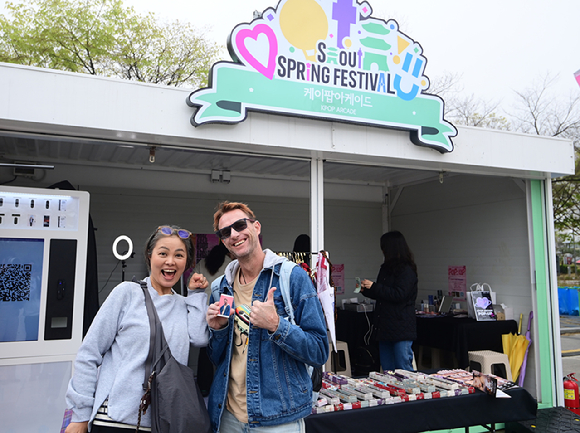 10일 서울 여의도 한강공원에서 열린 '2026 서울 스프링 페스티벌' 케이팝아케이드 부스에서 외국인 관광객이 포토카드 만들기 체험을 하고 즐거워하고 있다. [사진=정소희 기자]