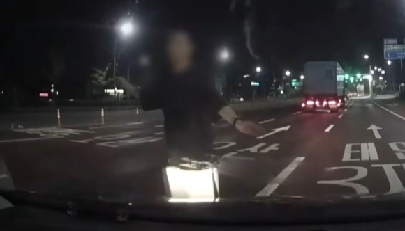 새벽 시간 한 도로에서 돌연 한 괴한을 마주해 차량까지 파손당한 남성의 사연이 전해졌다. 사진은 신원 미상의 남성이 운전자 차량을 막고 있는 모습. [사진=JTBC 방송화면 캡처]