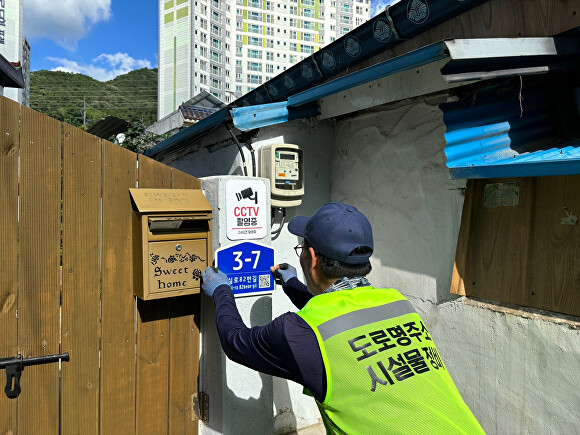 한 시설물 정비 관계자가 노후화된 건물번호판을 교체하고 있다.[사진=광양시]