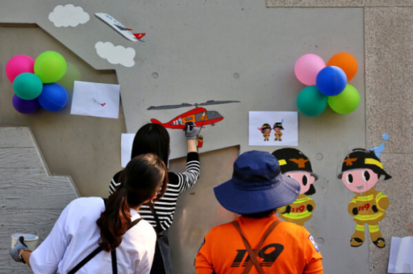 서울 광진구 능동 광나루안전체험관에서 20일 티웨이항공 임직원과 소방관이 벽화 그리기 봉사활동을 진행하고 있다. [사진=티웨이항공]
