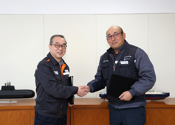 정인섭 한화오션 경영지원실장 사장(왼쪽)과 강주용 전국금속노조 경남지부 한화오션지회 수석부지회장이 발전적인 노사관계 구축을 위한 합의서에 서명한 뒤 악수하고 있다. [사진=한화오션]